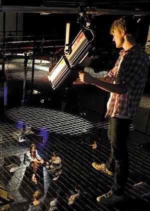 Tekniker justerar en scenstrålkastare ovanför en teaterscen